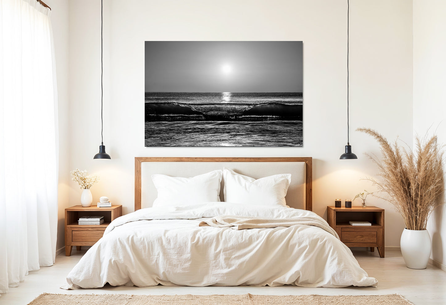 A black and white sunrise ocean wave print art piece displayed on a light beige wall above a neatly made bed in a modern, minimalist bedroom.