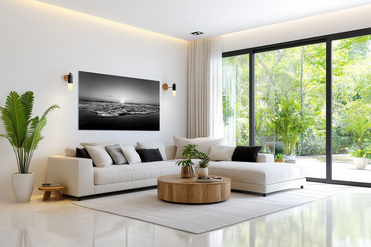 Black and white print of the July 2, 2026 Playalinda Beach, Florida sunrise displayed in a bright modern living room with greenery
