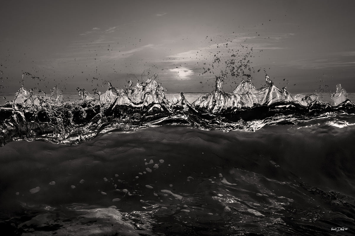 Black and white print of the August 24, 2026 Playalinda Beach sunrise, backlit breaking wave